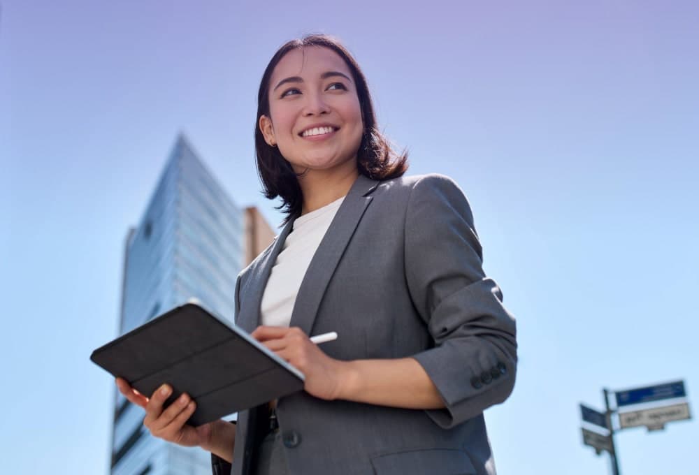 A woman holding a tablet in her hands and smiling with confidence