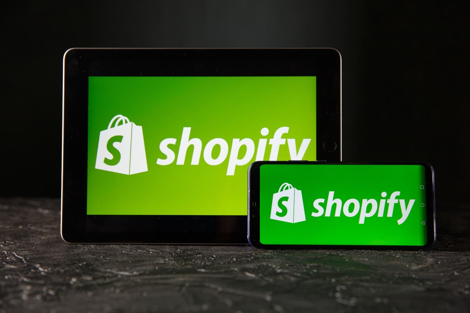 An iPad and and a cellphone with the Shopify logo on their screens